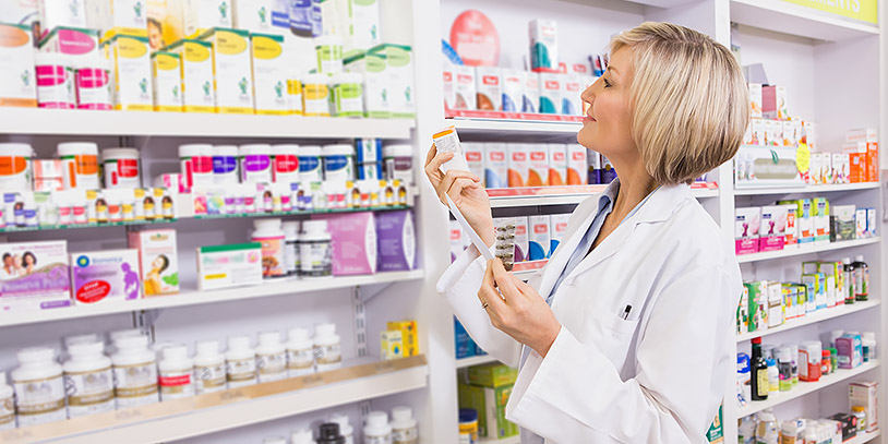 smiling pharmacist holding prescription and medicine in the phar